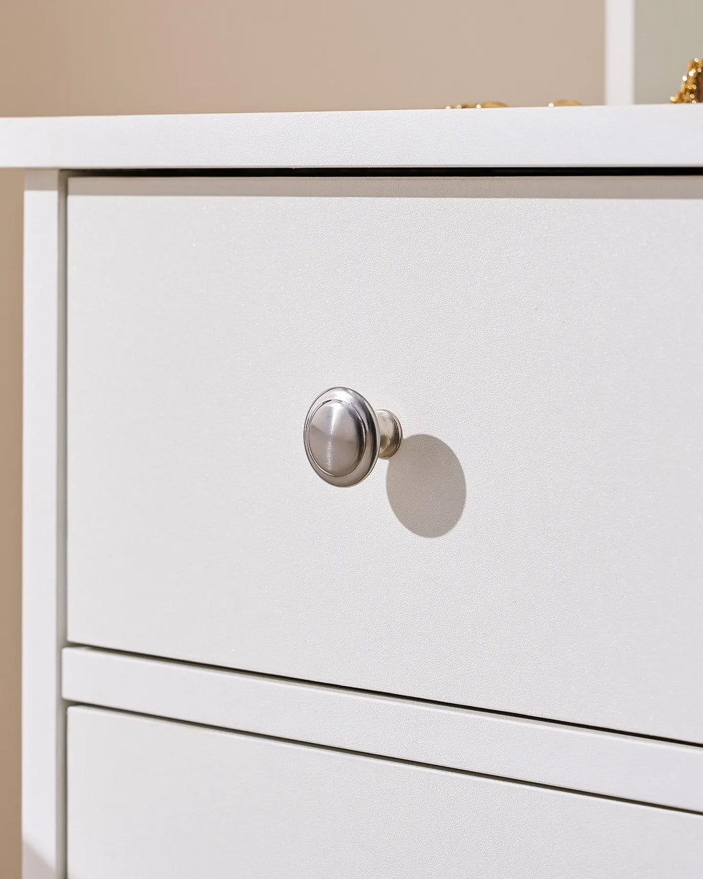 Close-up of a white dressing table drawer featuring a round metallic knob, showcasing a sleek and modern design.