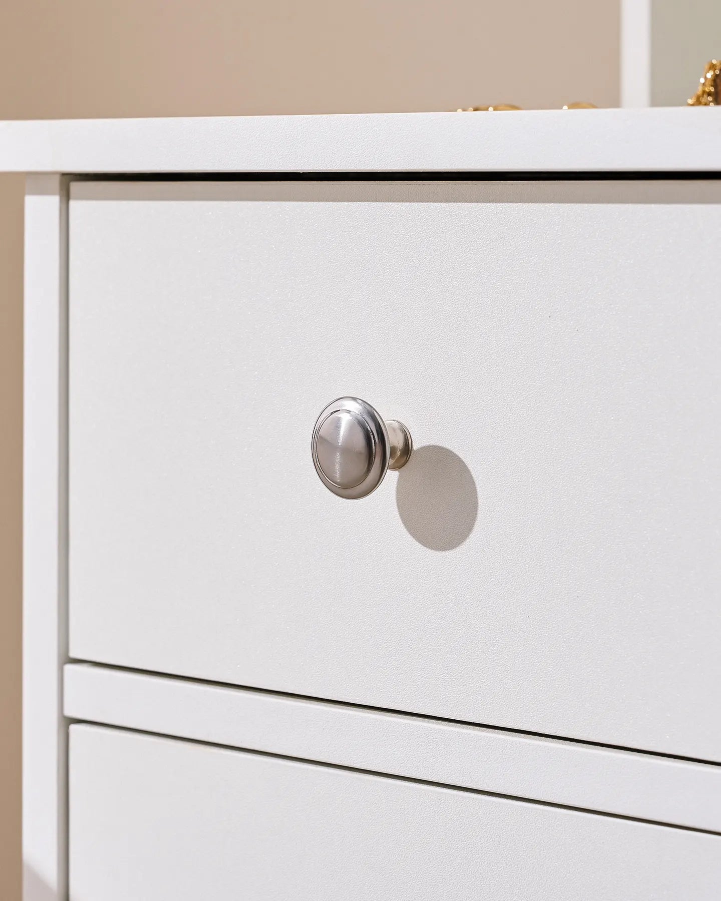 Close-up of a white dressing table drawer featuring a round metallic knob, showcasing a sleek and modern design.