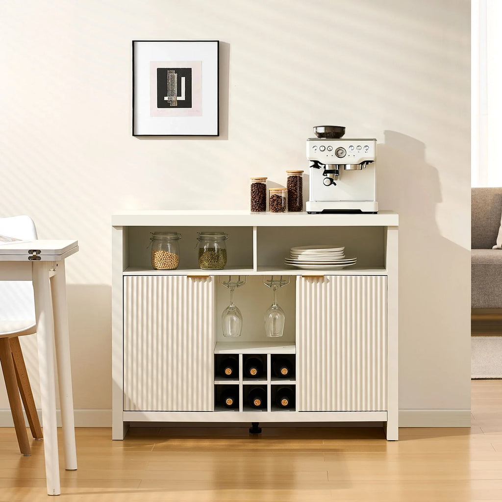 Warm white wine bar cabinet featuring fluted panel doors, brushed gold handles, and storage for wine bottles and glasses.