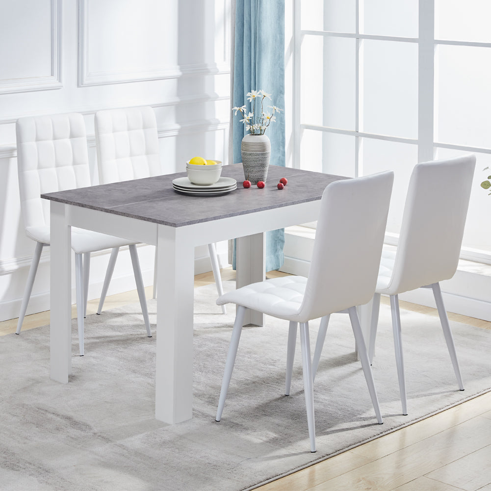 Rectangular grey MDF dining table with a white base, accompanied by modern white upholstered chairs. Decorative vase on table.