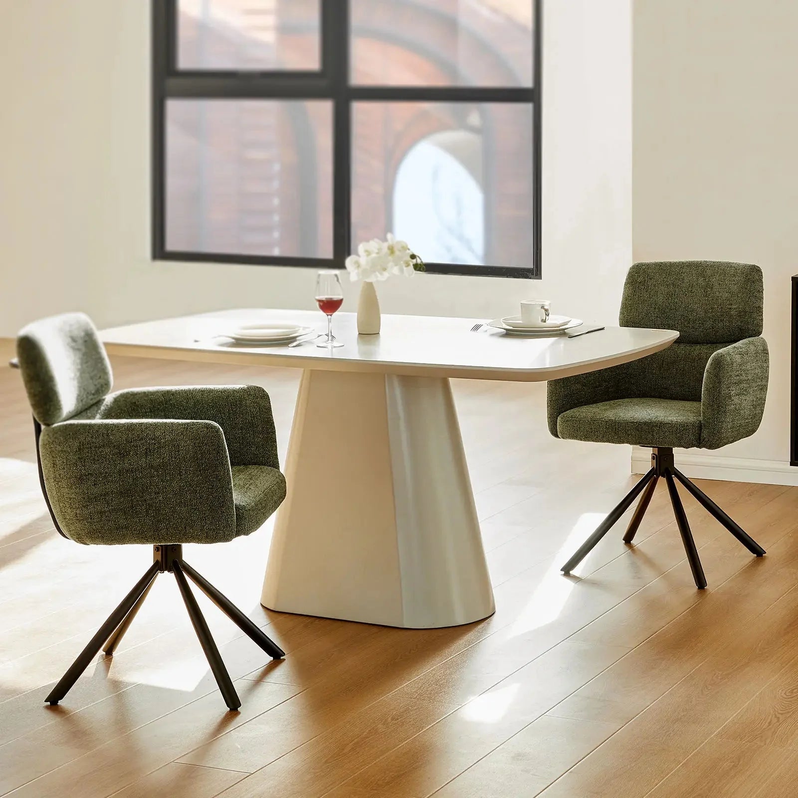 Chenille swivel chair in olive green with sleek black metal base, positioned at a modern dining table.