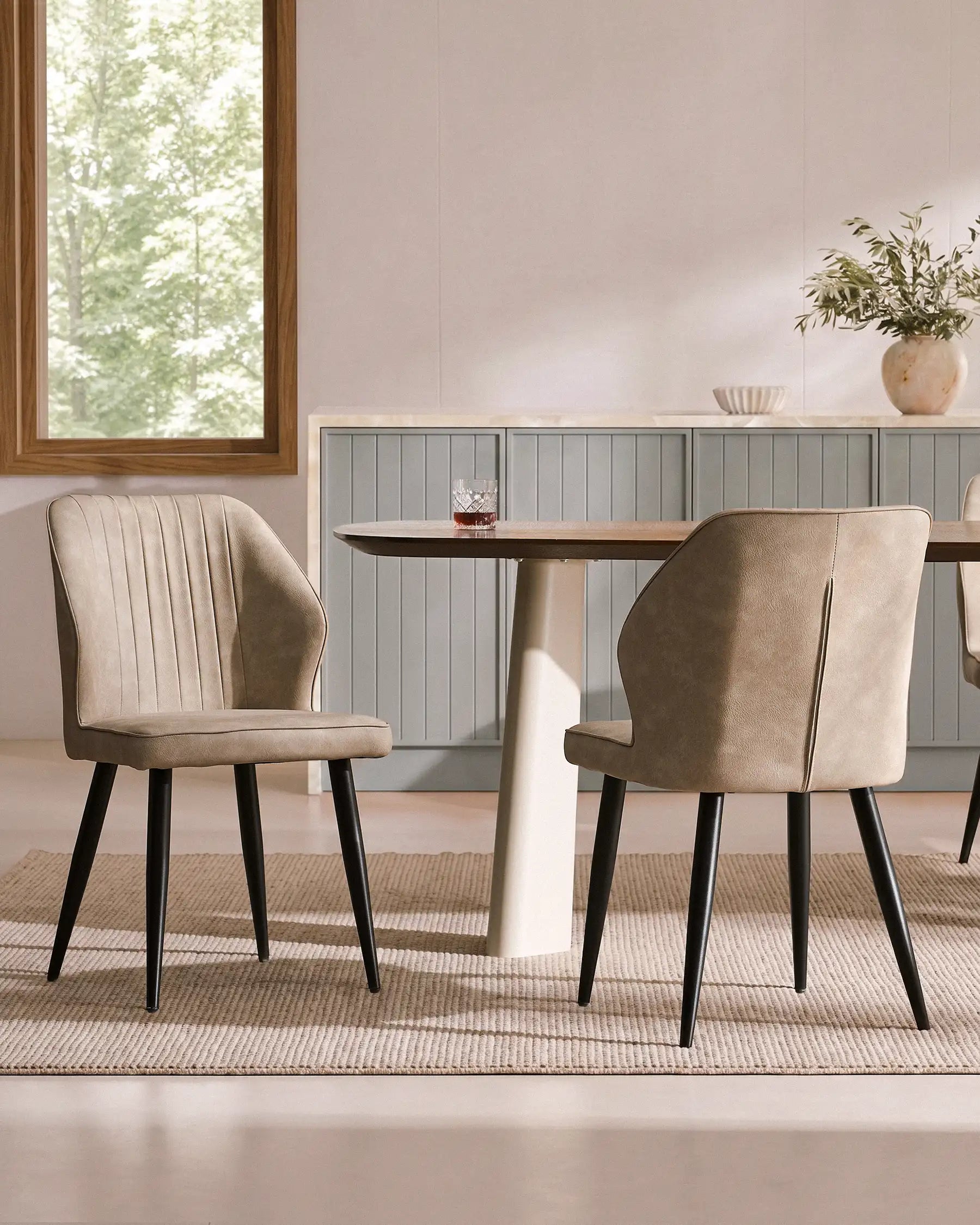 Set of 6 Danforth faux leather dining chairs in beige, featuring black metal legs and ribbed backs, arranged at a dining table.