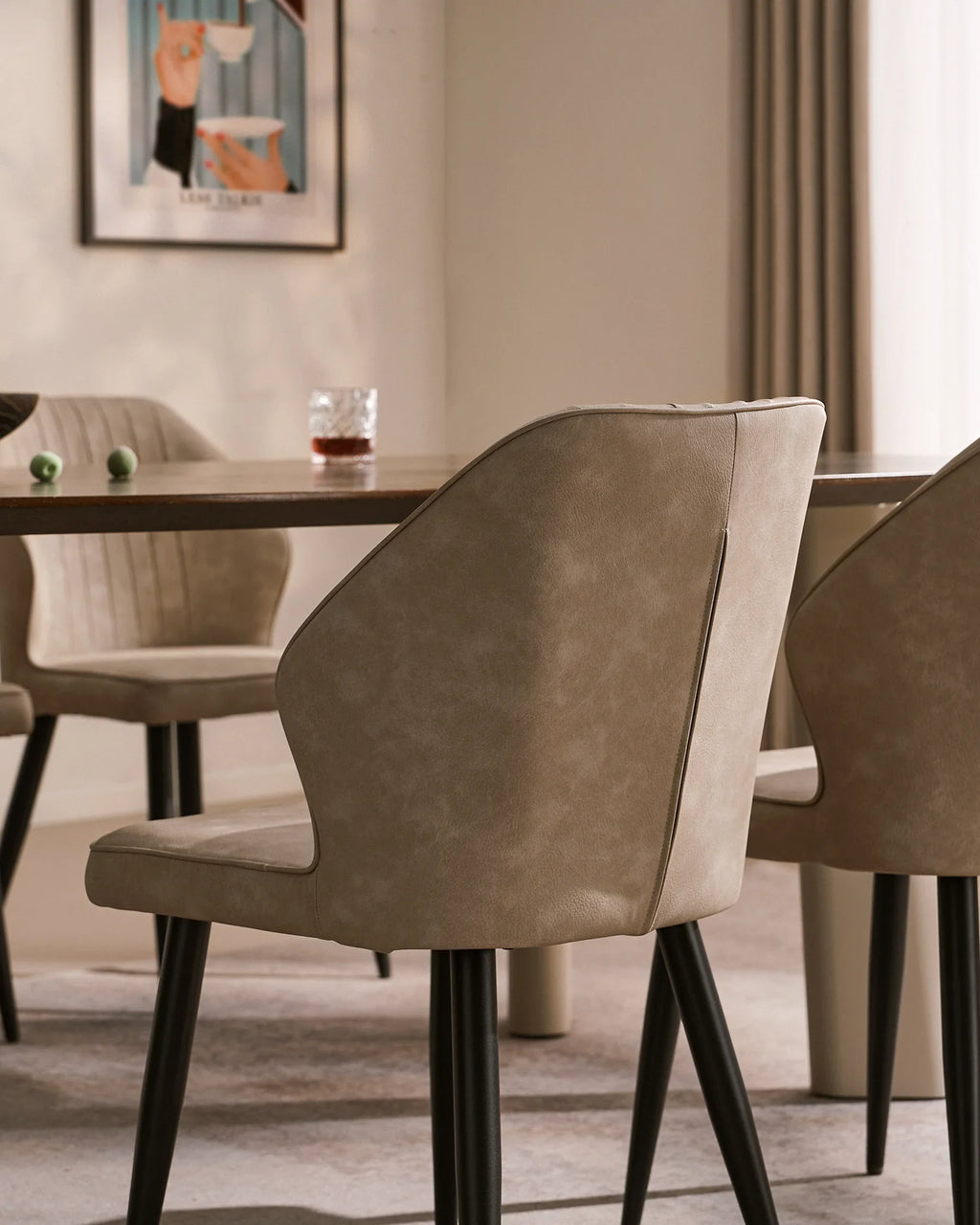 Beige and light grey faux leather dining chairs with black metal legs, styled around a wooden table in a dining room setting.