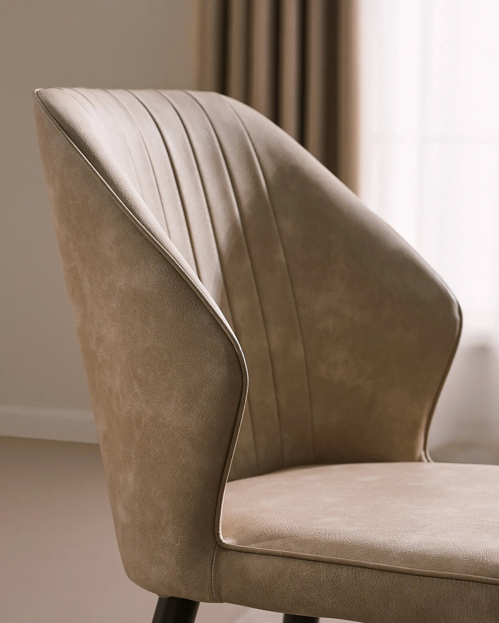 Beige faux leather dining chair with cushioned seat, feature a sleek, high back and vertical stitching, paired with black metal legs.