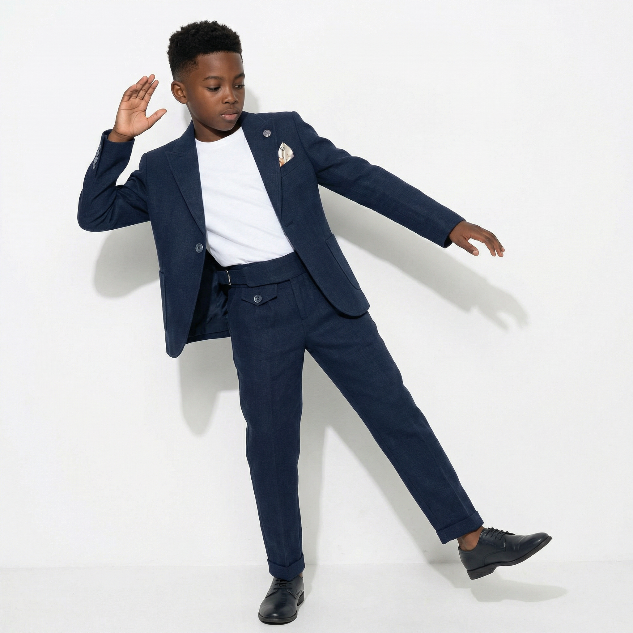 Navy blue formal suit for boys featuring a structured blazer, tailored trousers, and a white undershirt, styled playfully.