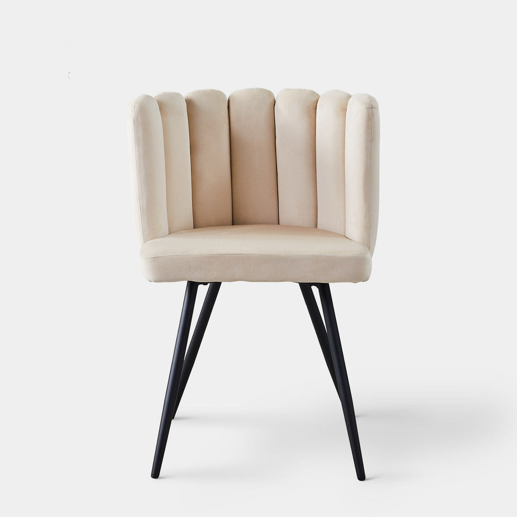 Tufted velvet accent dining chair in beige with a petal-shaped backrest and tapered black metal legs.