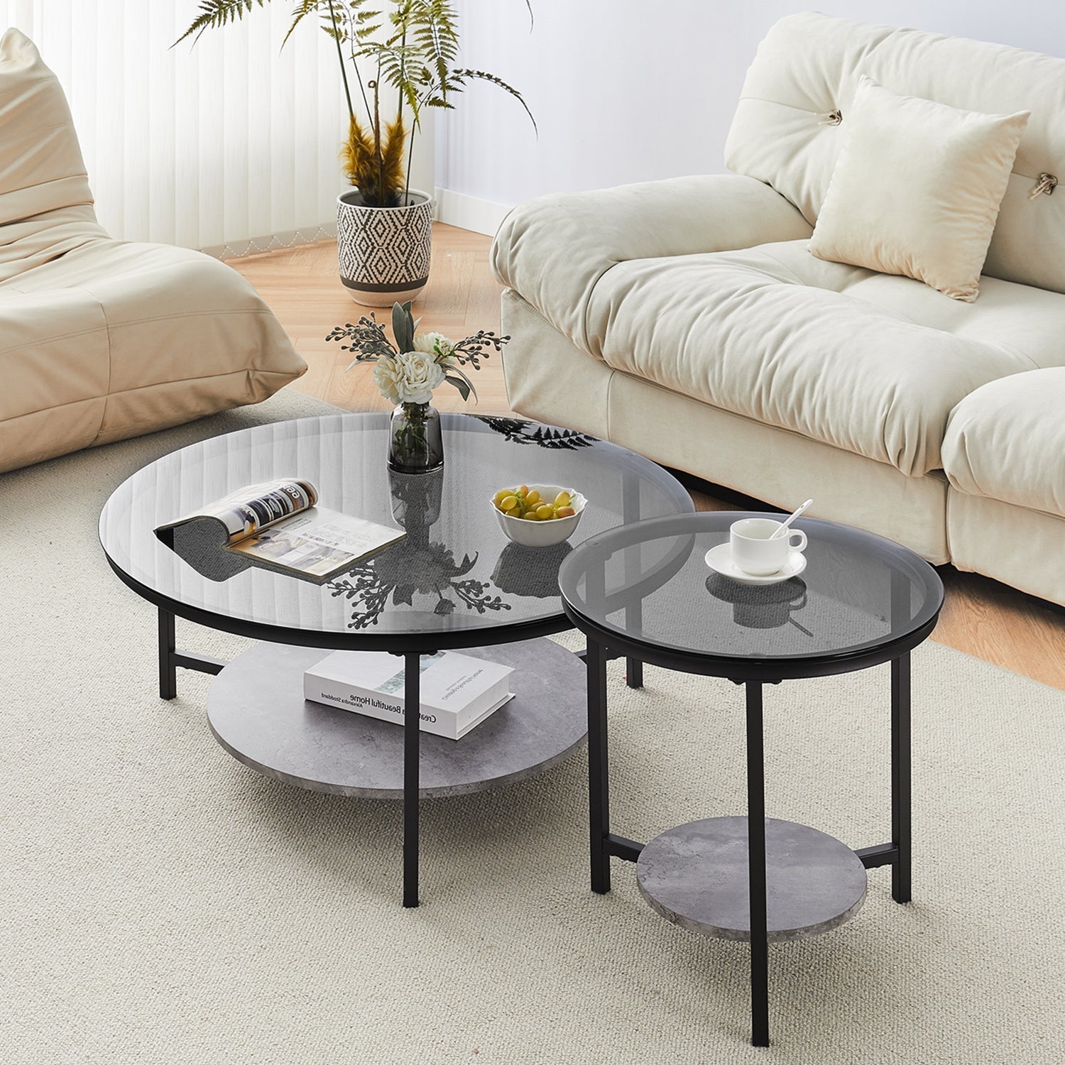 Black tempered glass coffee table set with round tops, metal legs, and a grey marble bottom shelf, styled in a living room.