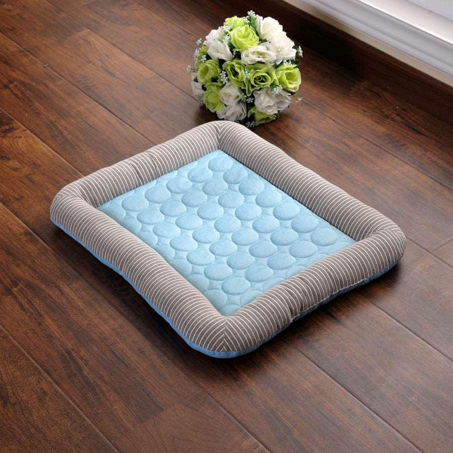 Light blue cooling pad with a striped gray border, designed for pets, placed on a wooden floor.